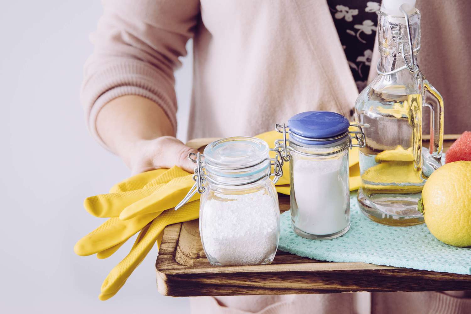 woman holding vinegar, baking soda, and citric acid cleaning supplies