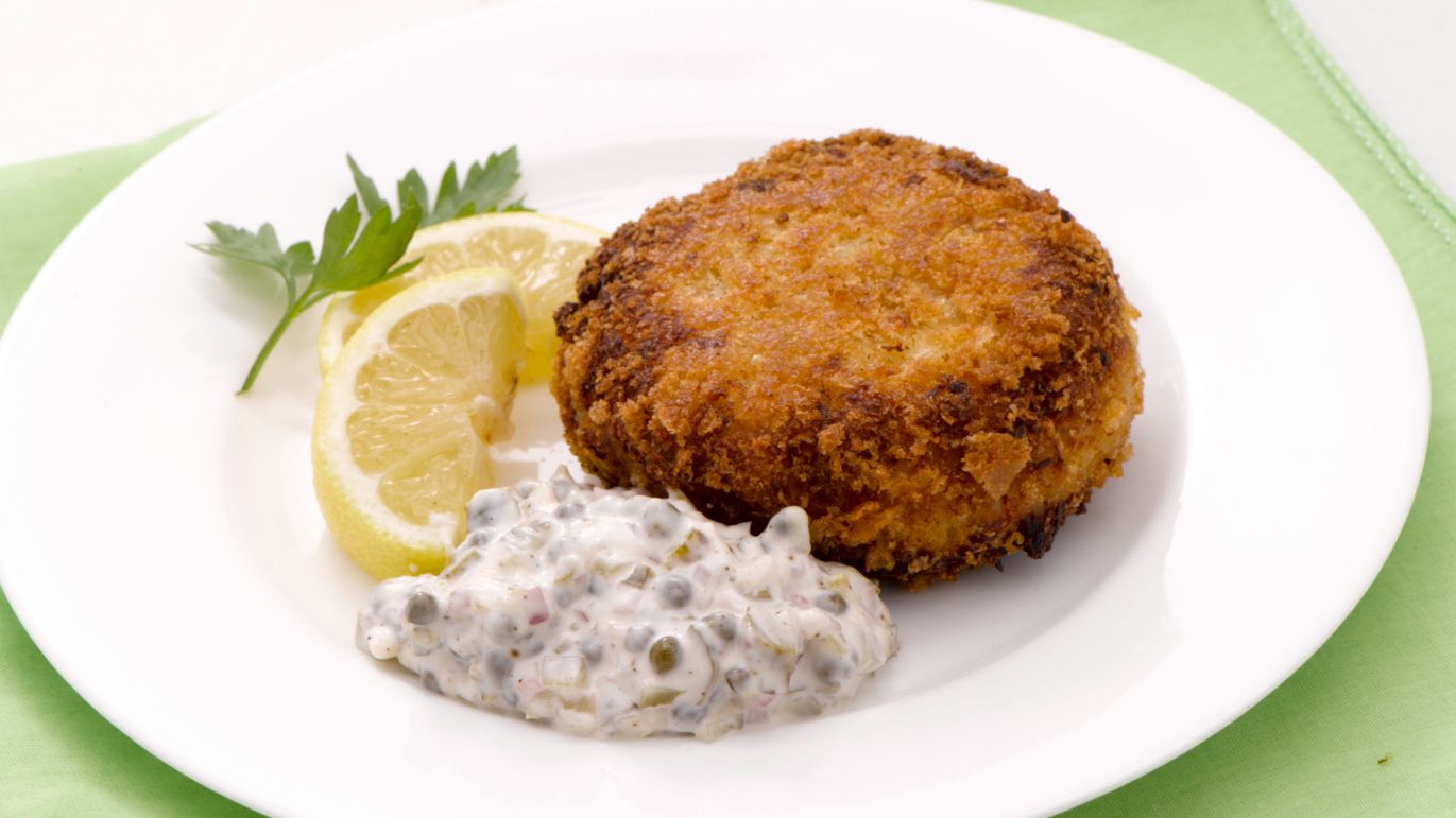 tartar sauce on plate with fish cake and lemon slices