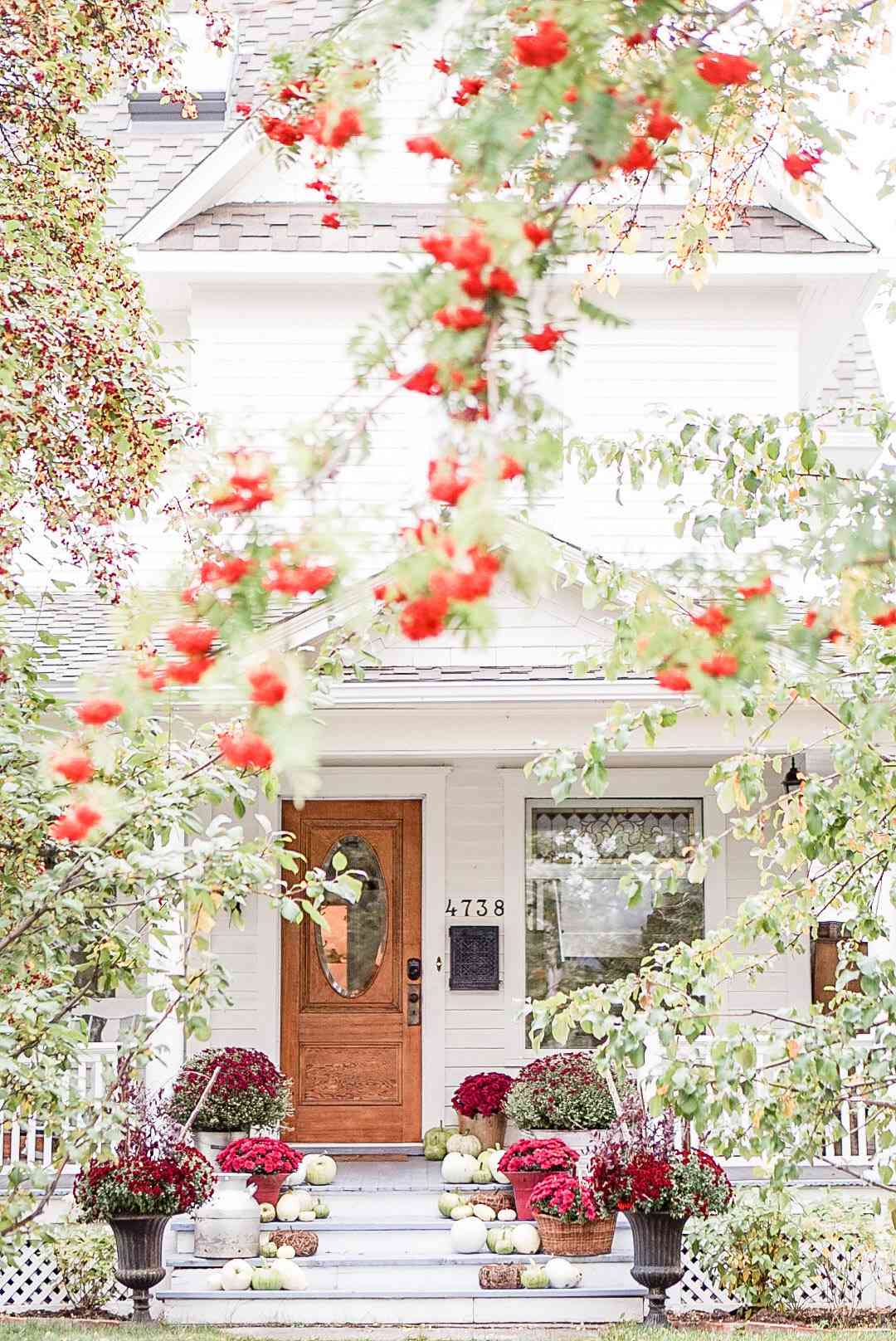 fall porch with green pumpkins and burgundy mums