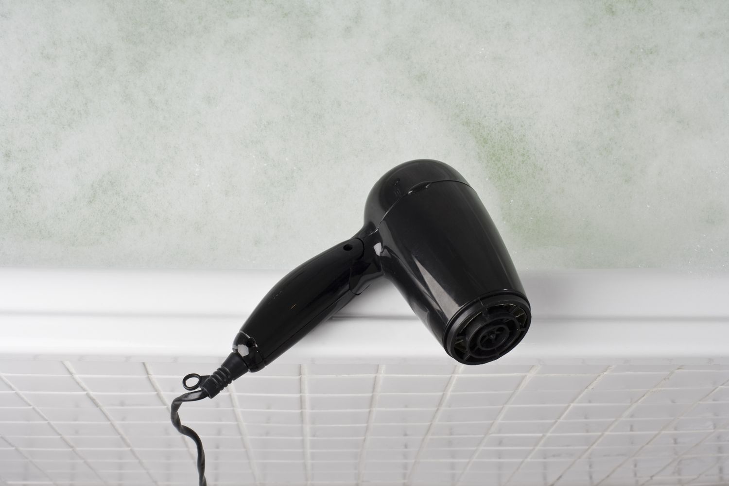 A hair dryer placed on the edge of a bathtub