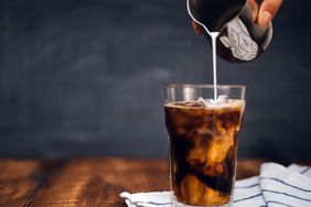glass of iced coffee with milk being poured into it