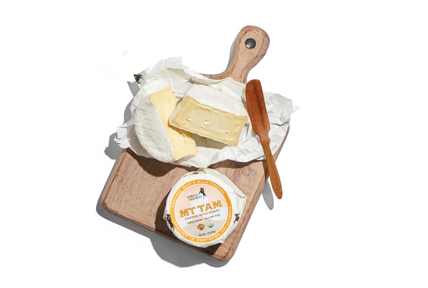 Cheese on a wooden board with a knife and Mt Tam cheese container
