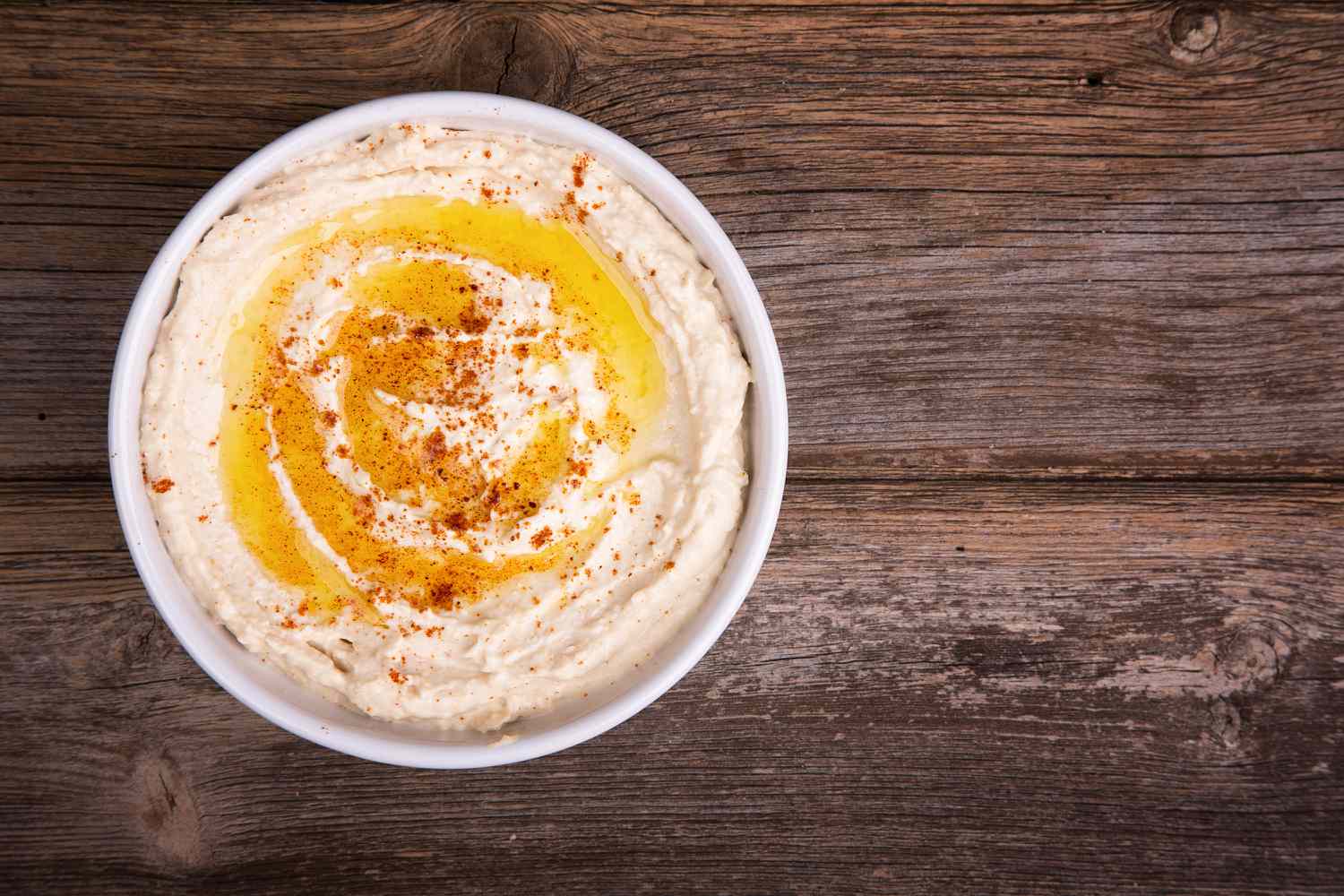 Bowl of Hummus on Wooden Background