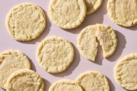 Several sugar cookies arranged on a surface one partially broken