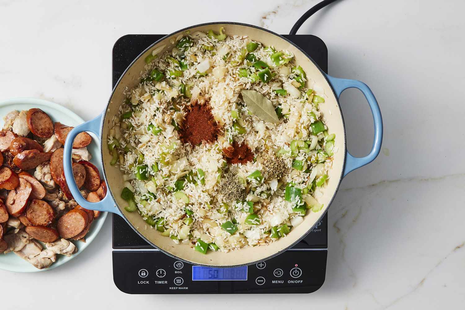 Vegetables, rice and spices in skillet with chicken and sausage