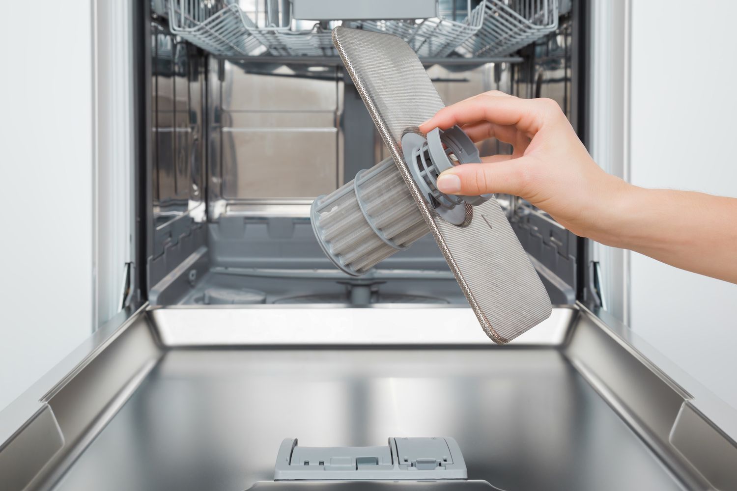 A person removing the filter from a dishwasher