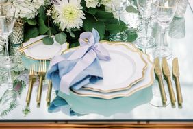 gold and white place settings with blue linens and floral centerpieces