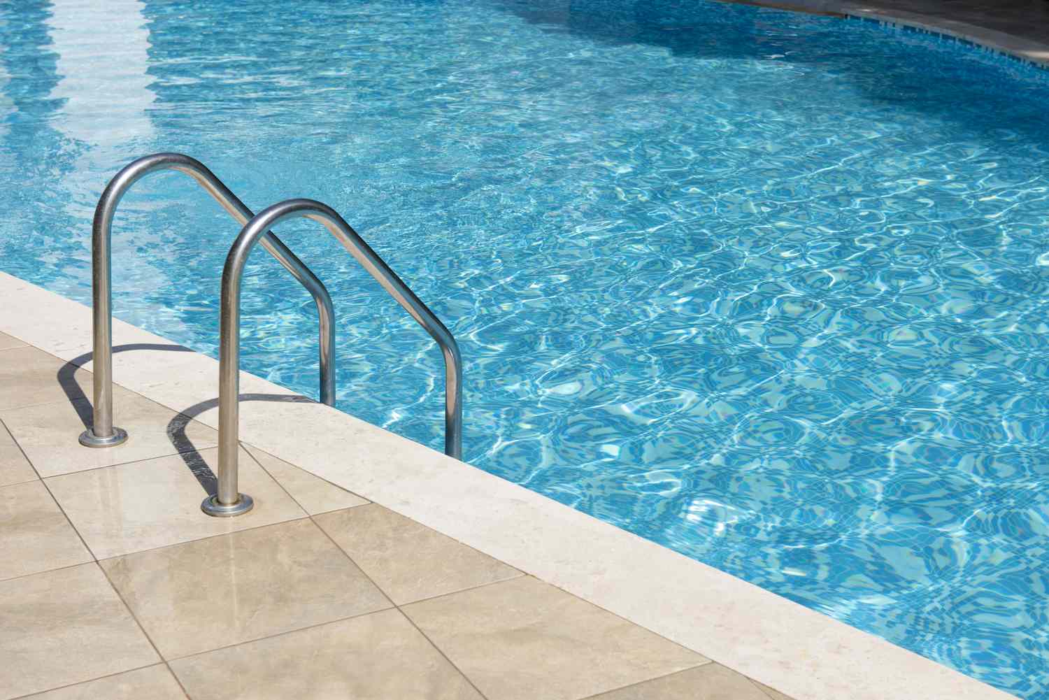A swimming pool with a metallic ladder and tiled poolside