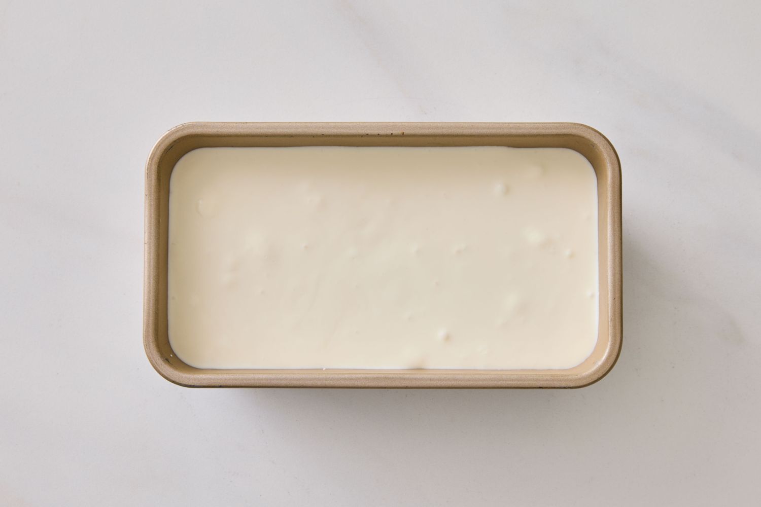 A rectangular container filled with vanilla ice cream