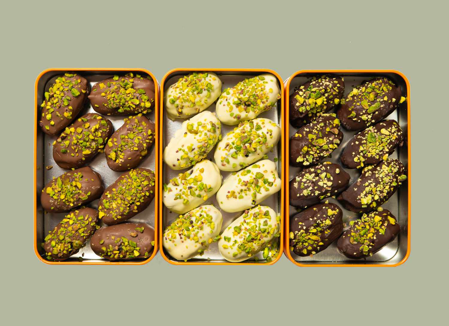 three tins of dipped dates on green background