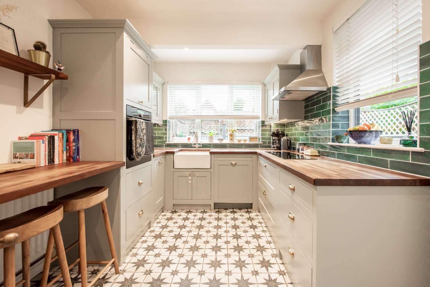 A kitchen interior with wooden countertops patterned tile flooring and green tiled backsplash