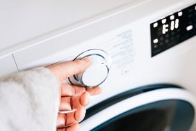Hand turning a knob on a washing machine