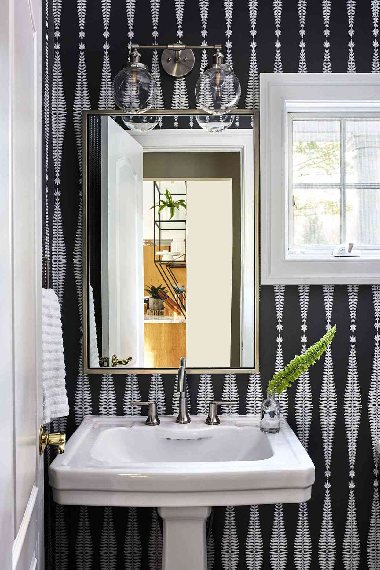 black patterned wallpaper in powder room with mirror and white sink