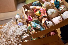 a woman holding a box of glass vintage Christmas tree toys