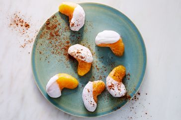 Orange wedges dipped in yogurt and sprinkled with powder arranged on a ceramic plate