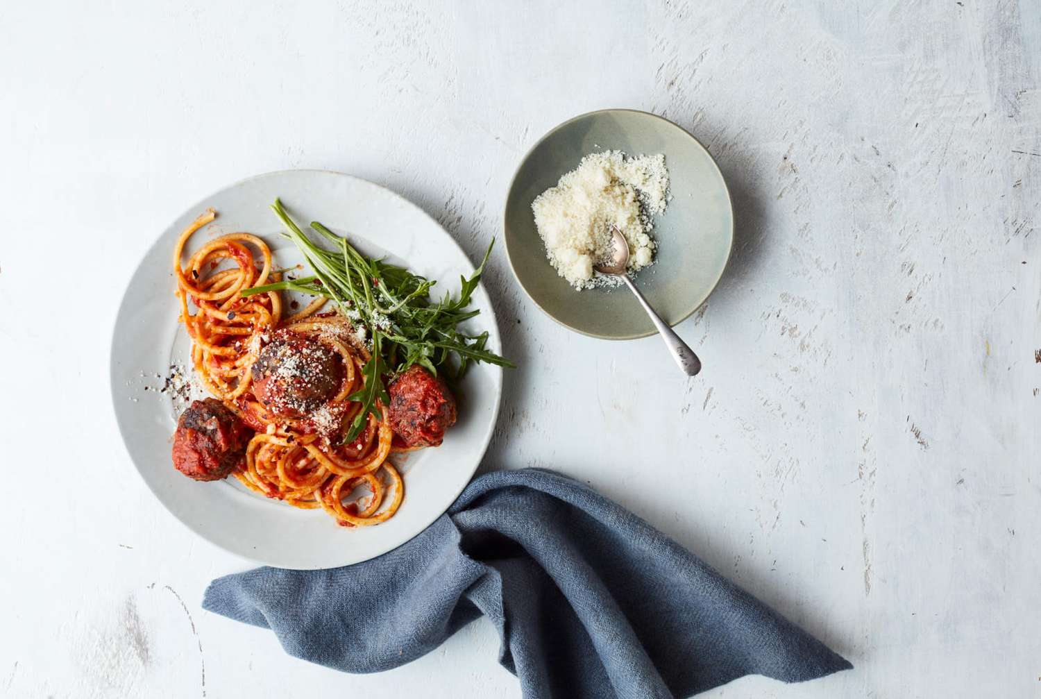 Spaghetti and meatball pasta and parmesan cheese on a table. 