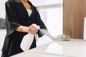 Person cleaning a countertop with a spray bottle and cloth