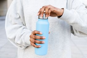 A person tightening the lid on a reusable water bottle