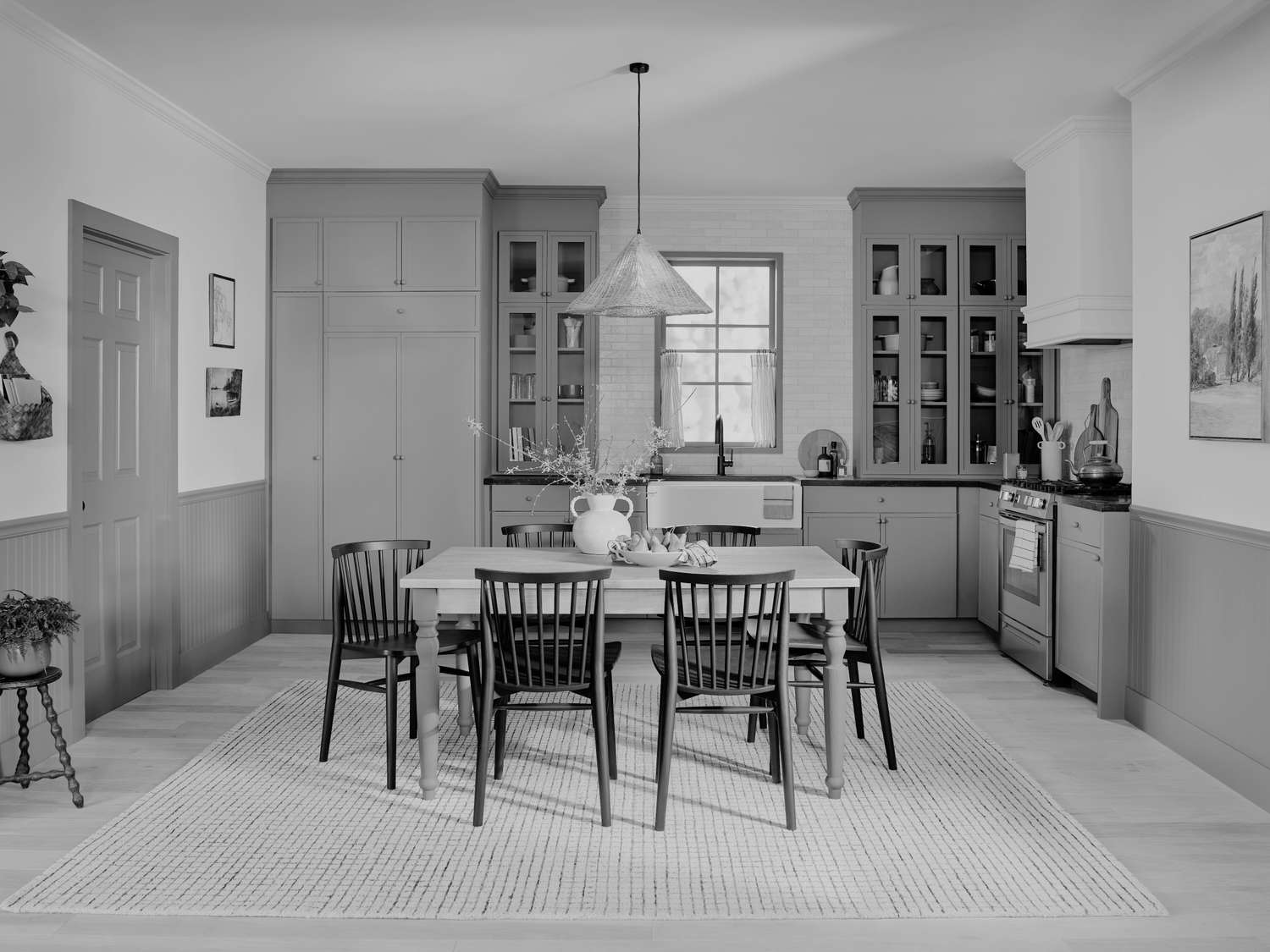 A kitchen with a dining table chairs and cabinetry in a classical interior design style