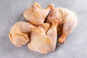 frozen chicken legs on grey surface