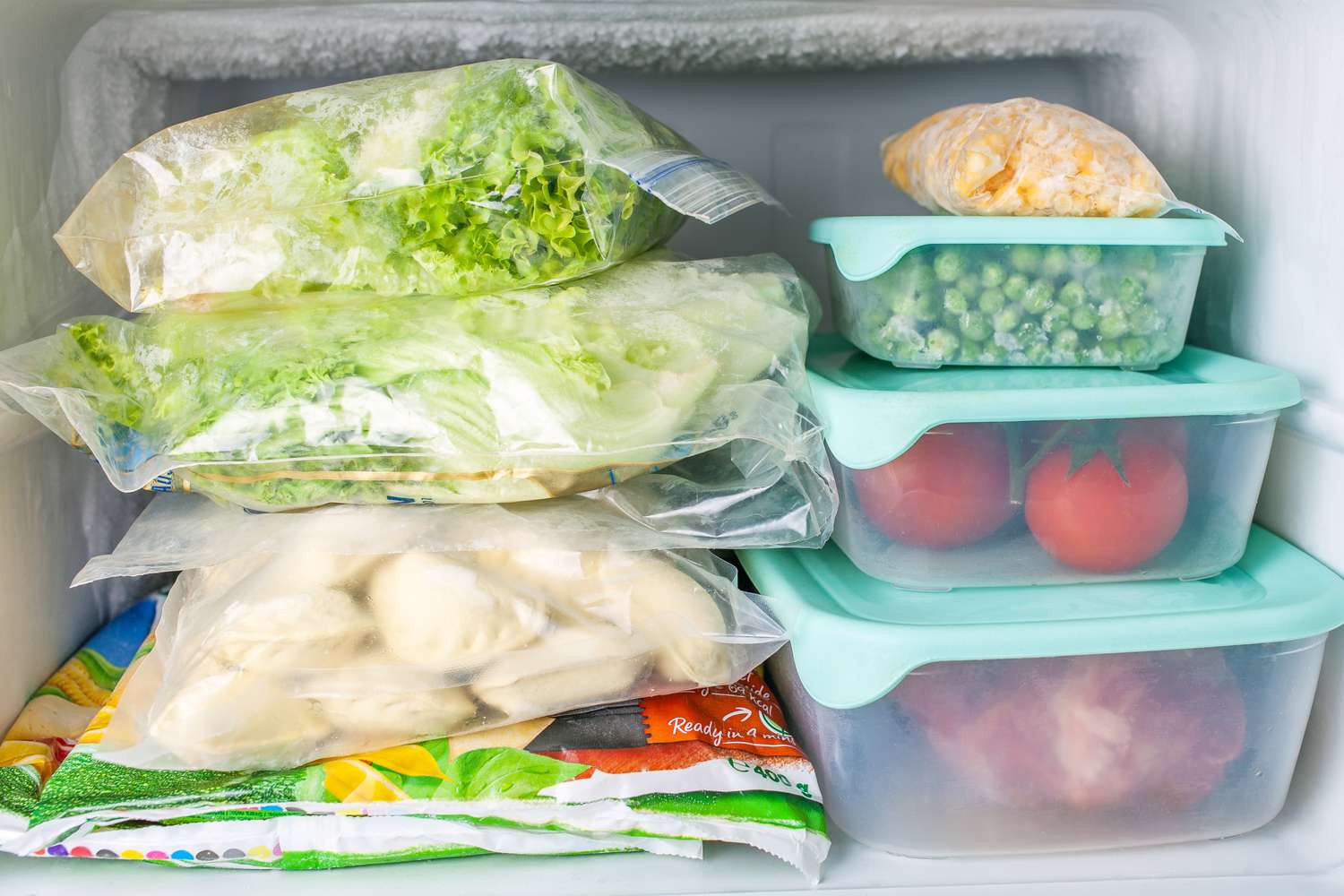 Stacked frozen food including vegetables in bags and containers arranged in a freezer