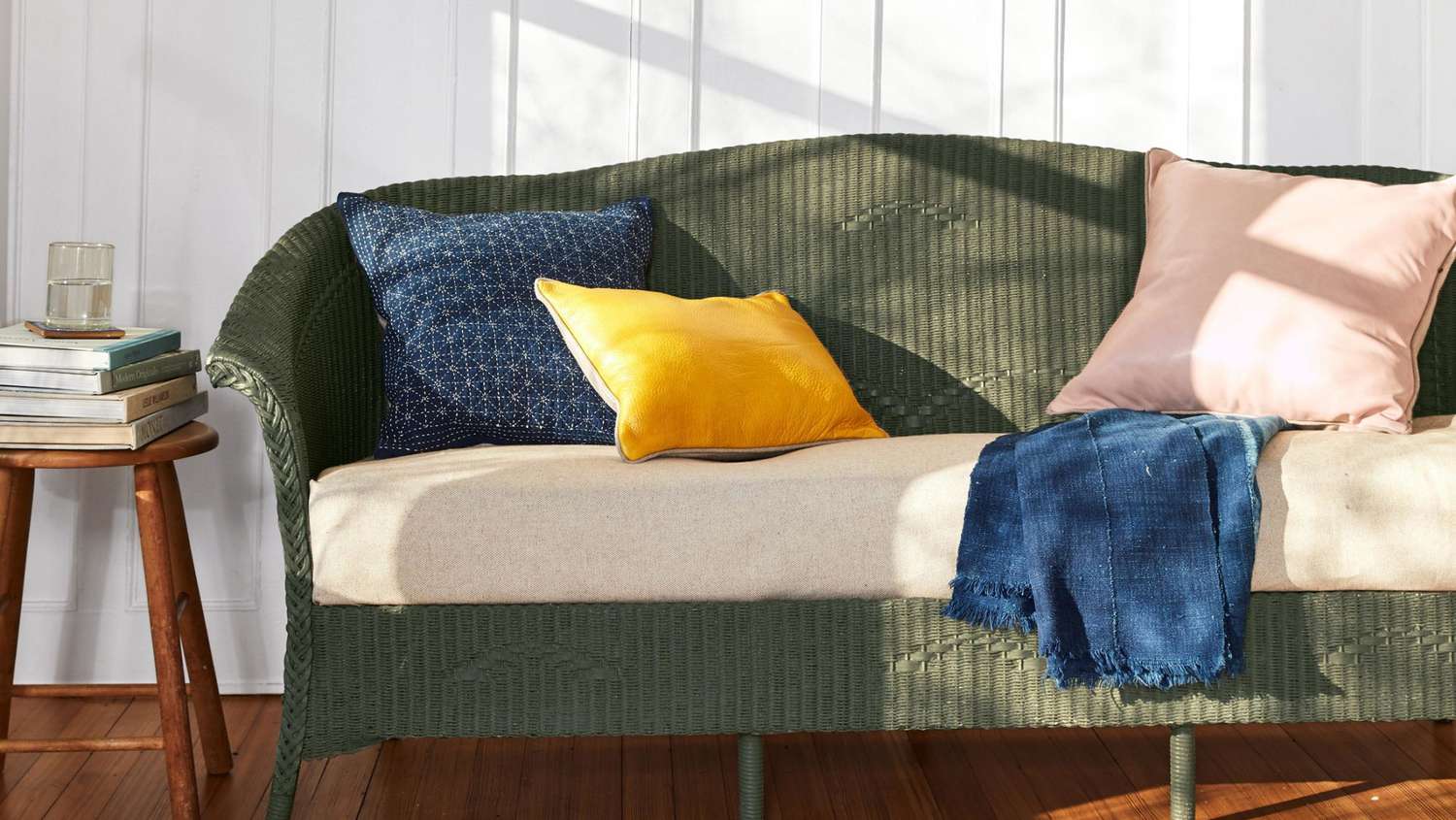 olive green painted wicker sofa with throw pillows