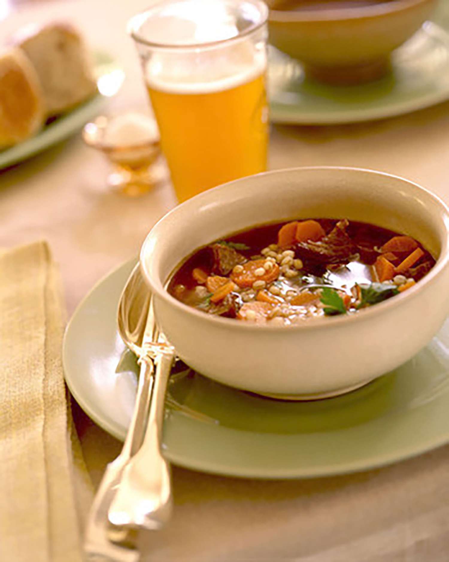 bowl of beef and barley soup with glass of beer