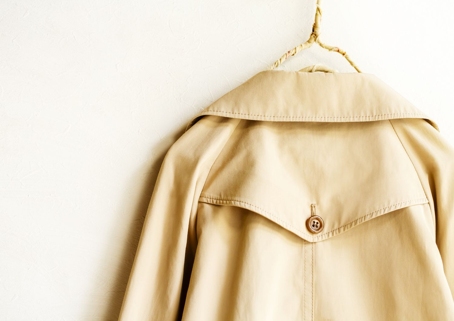 the back of a beige elegant trench coat isolated over white. Close up