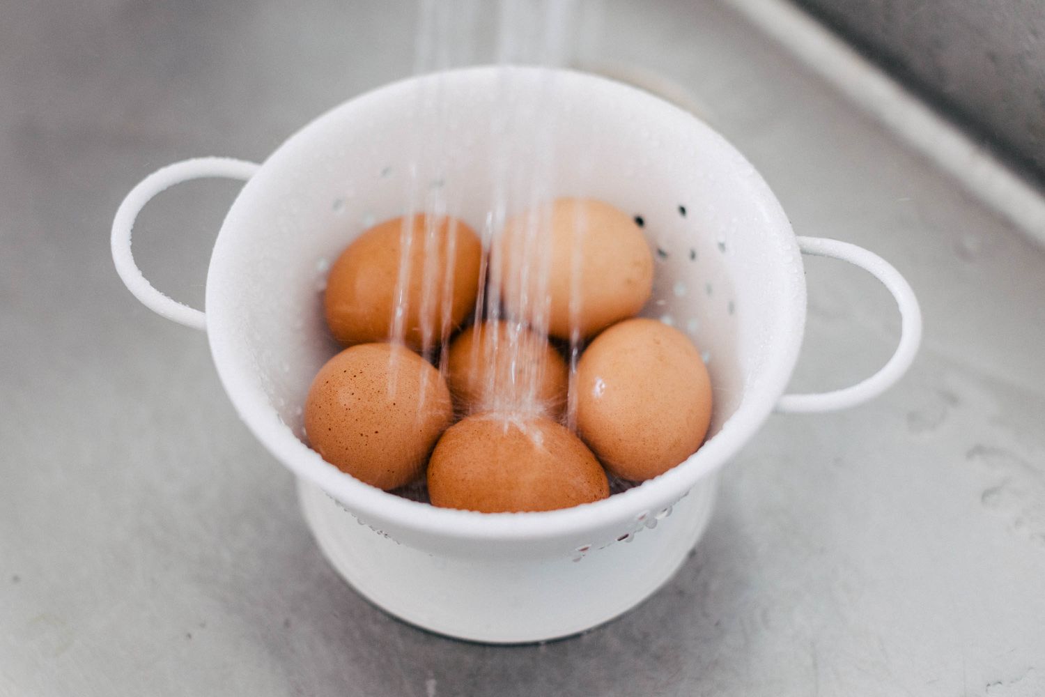 Running cold water over eggs in colander