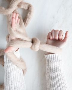 yarn looped around wrists for arm knit blanket