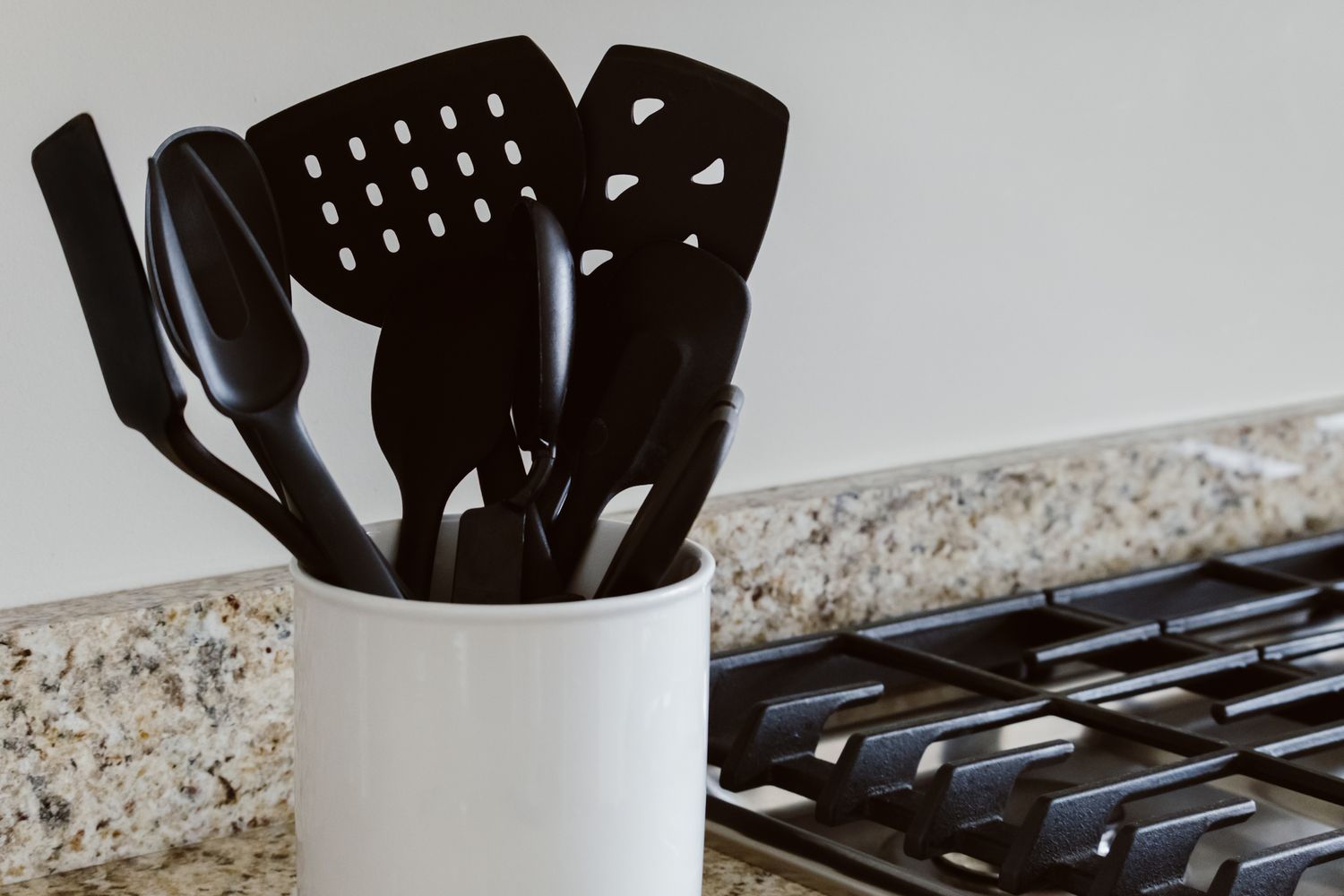 Plastic Kitchen utensils in a holder on a counter next to a stovetop