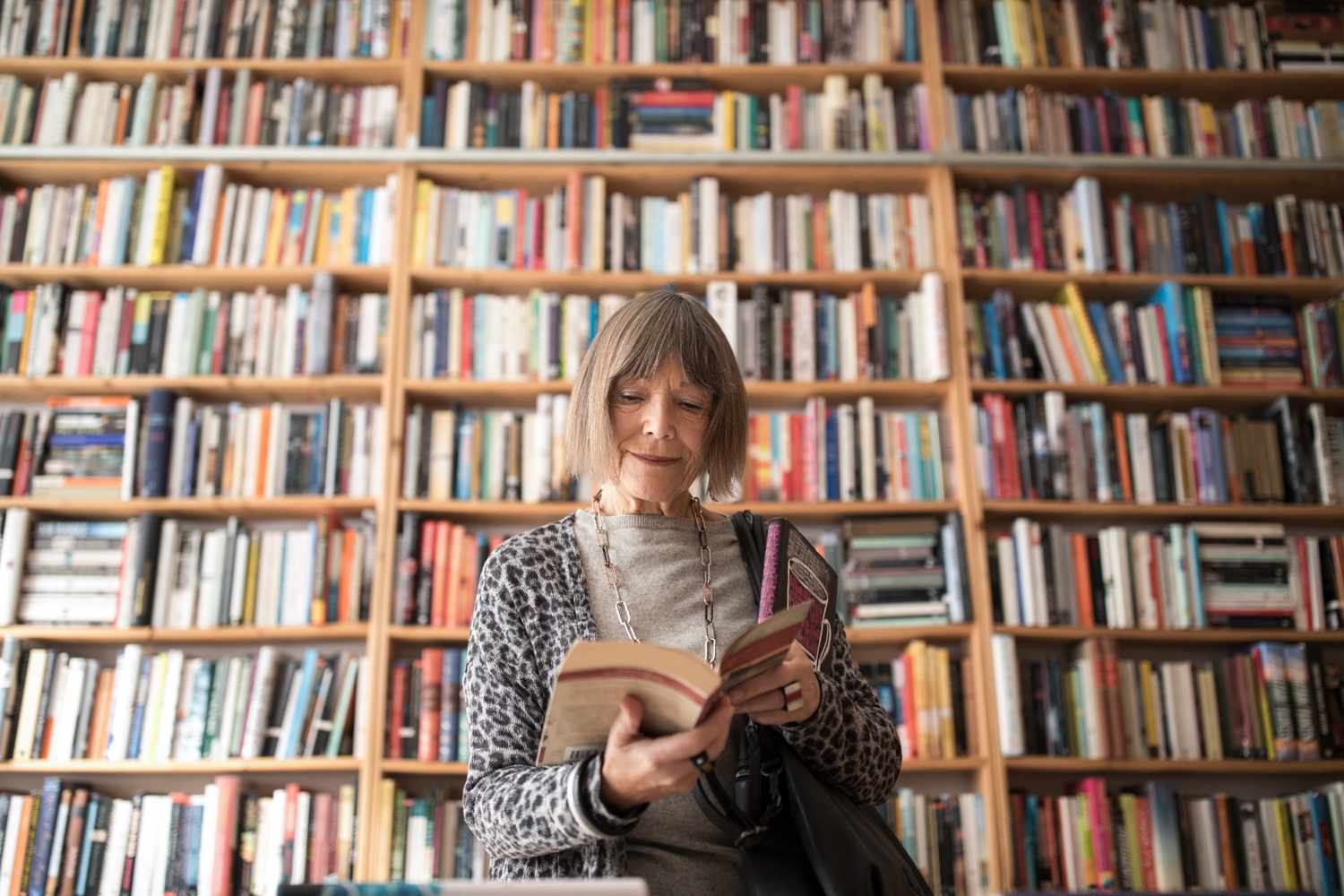 A woman reading in front of a large bookshelf
