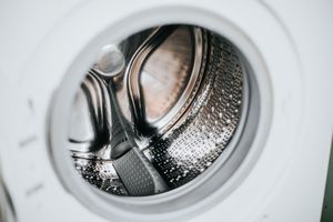A closeup view of the inside of a washing machine drum highlighting its metallic finish and perforations