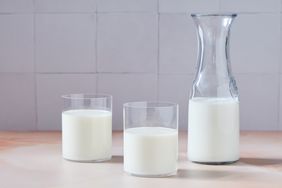 A carafe and two glasses of milk on a table