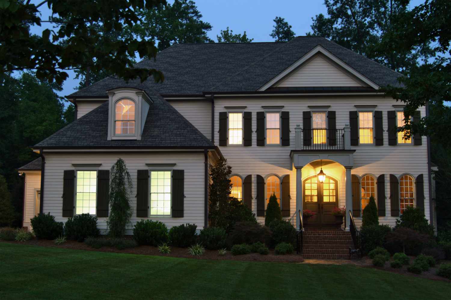 A large house at dusk with illuminated windows