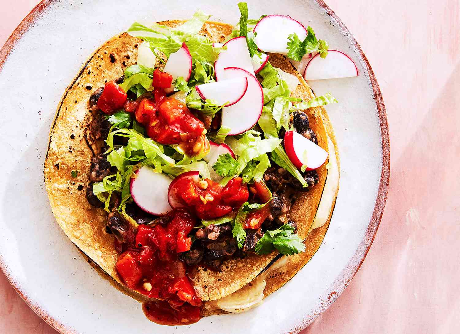 overhead view of a tostada on a pink surface