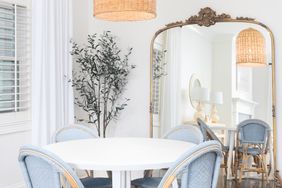 A dining area with a round table chairs and a large mirror reflecting part of the room