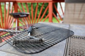 Outdoor table with a barbecue grill rack and a cleaning brush