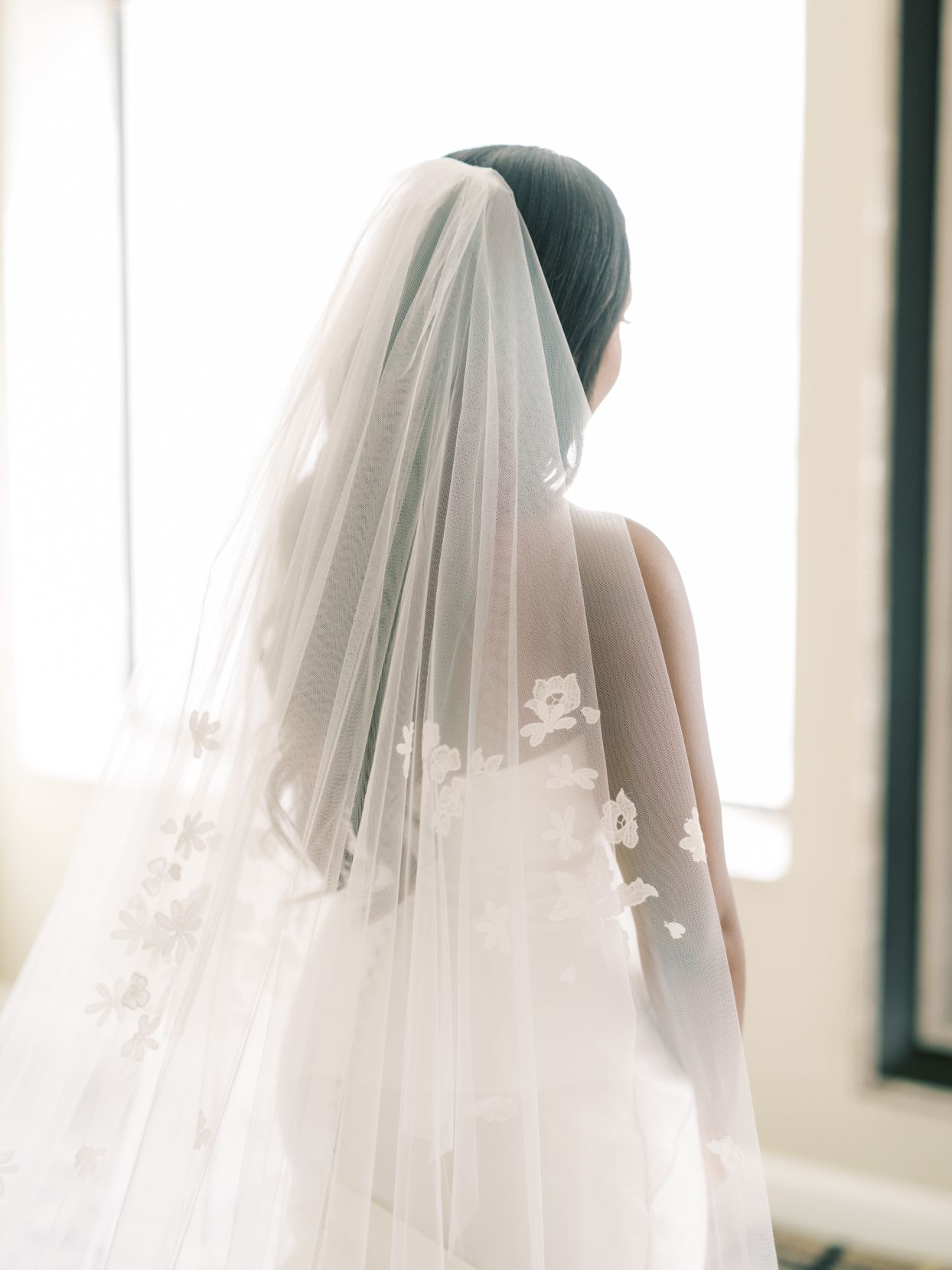bride looking out the window wearing delicate lace accented veil