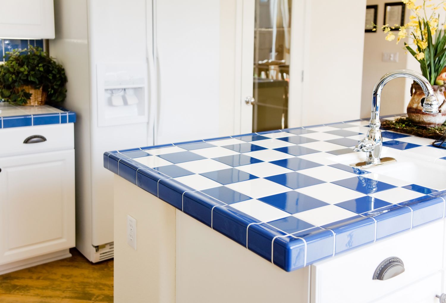 A kitchen countertop with a blue and white tiled surface and a faucet