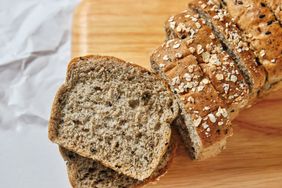 Sliced loaf of grain bread on a wooden cutting board