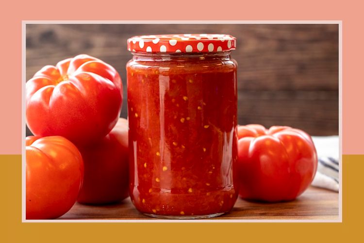A jar of tomato sauce next to several whole tomatoes