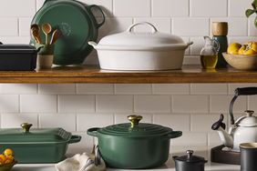 Various cookware items on kitchen shelves including Dutch ovens and a kettle