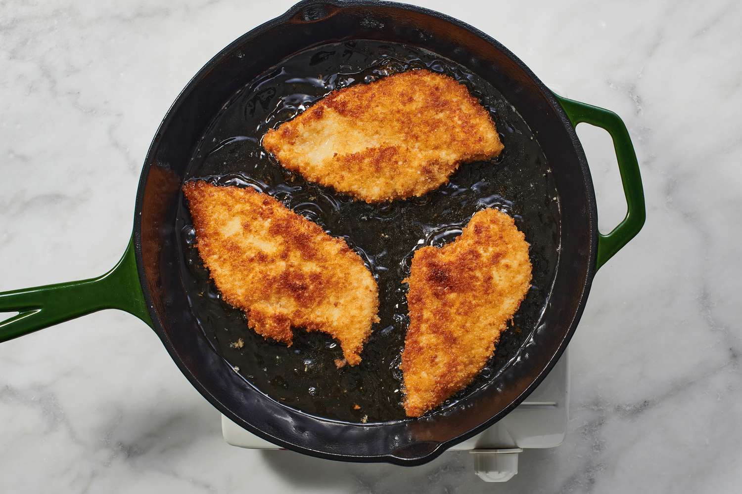 breaded chicken breasts cooking second side in skillet