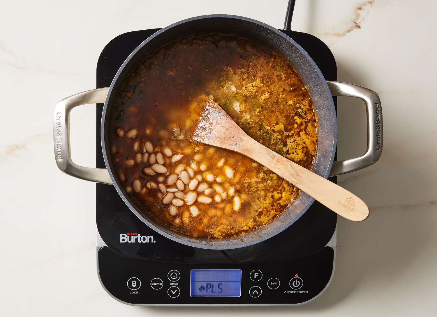 chili with white beans in a pot with a wooden spoon