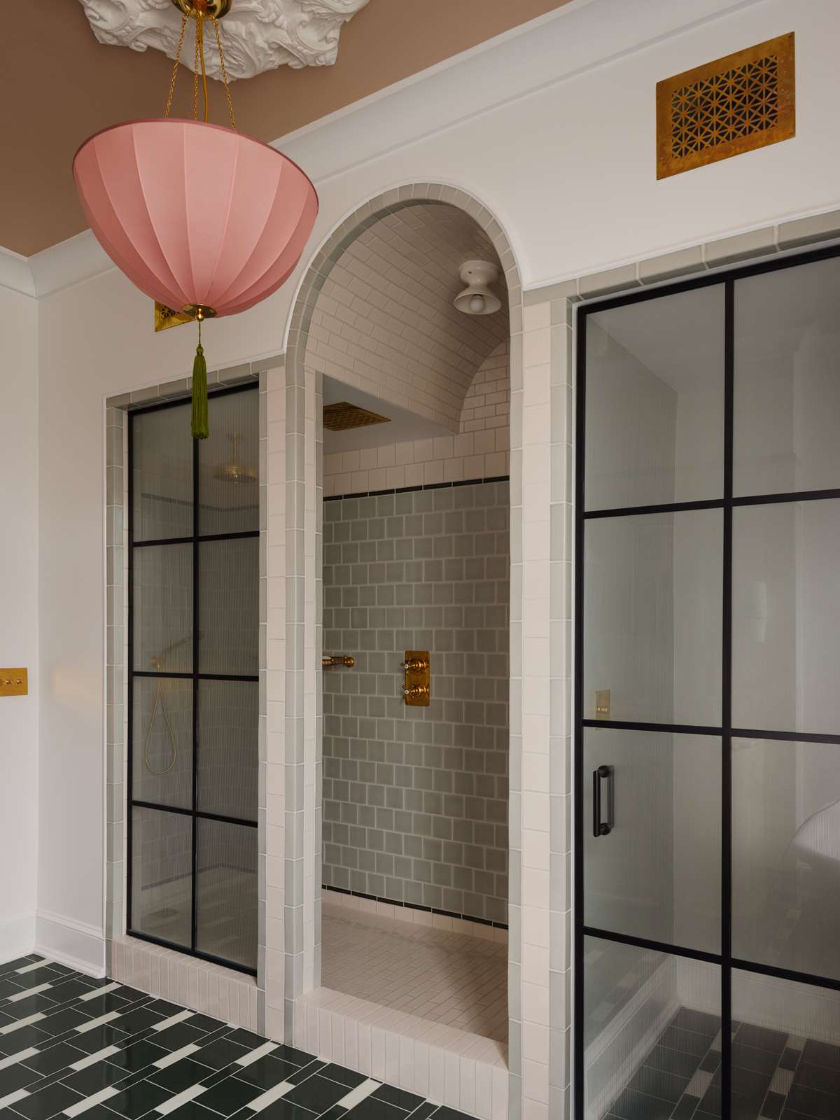 a walk-in shower with pink pendant light nearby