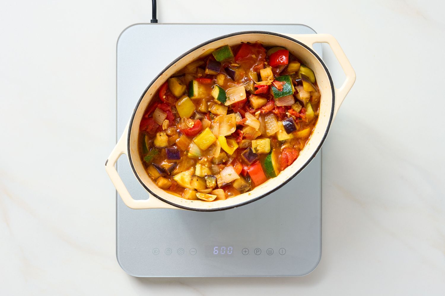 A dish of ratatouille cooking in a pot on an induction stovetop