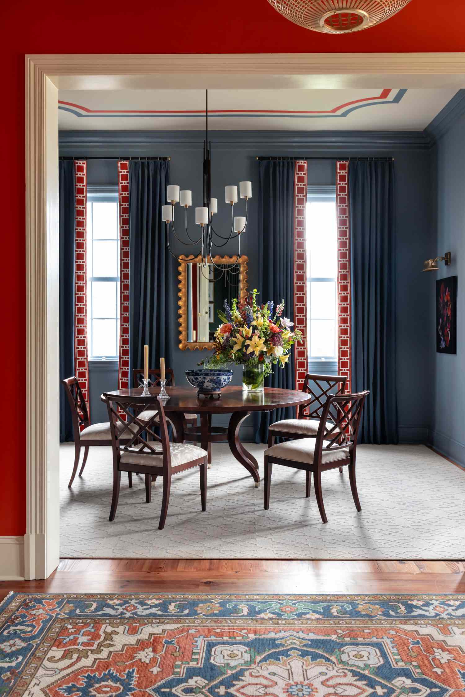 Elegant dining room with a round table floral centerpiece and ornate decor featuring tall curtains and modern lighting