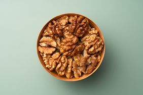 A bowl filled with shelled walnuts on a plain background