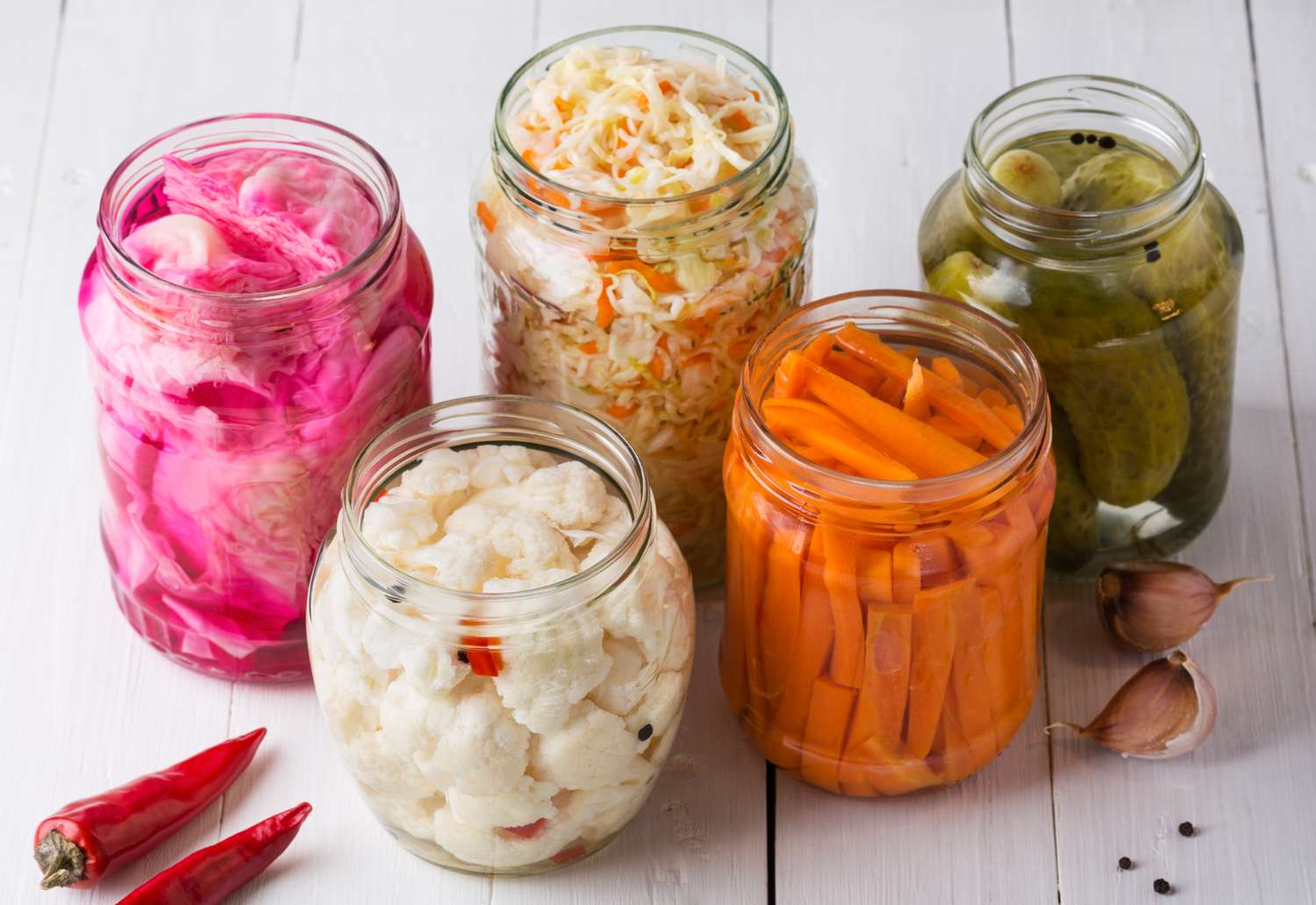 fermented foods including sauerkraut and pickles in glass jars without lids